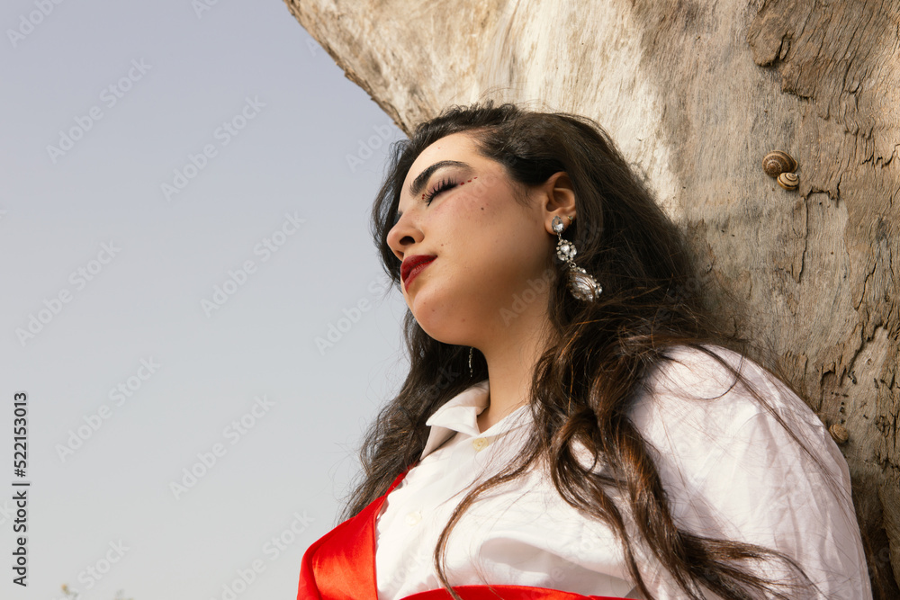 Beautiful young girl with long black hair wearing red dress in nature ...
