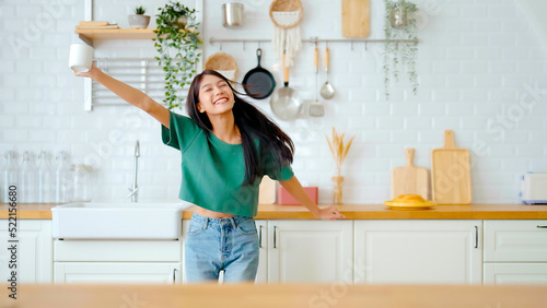 Fotografie Asian young woman dancing in kitchen room