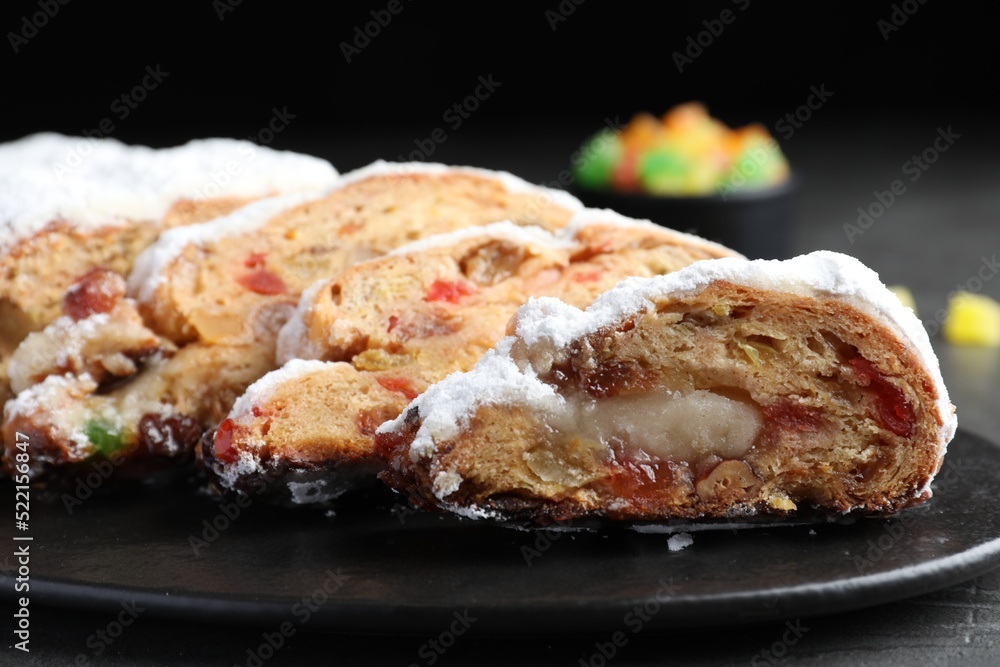 Traditional Christmas Stollen with icing sugar on black plate, closeup Traditional Christmas Stollen with icing sugar on black plate, closeup