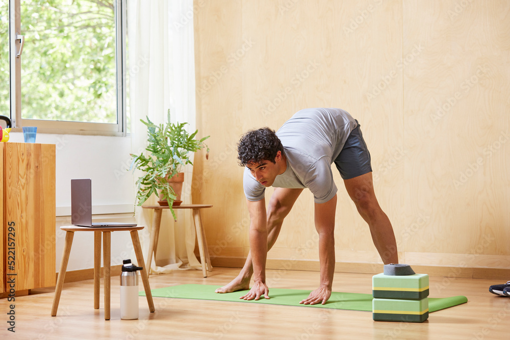 Focused man doing online yoga at home Focused man doing online yoga at home