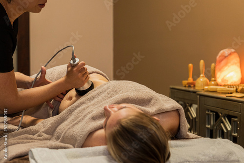 Woman lying down in a spa room for a laser massage photo