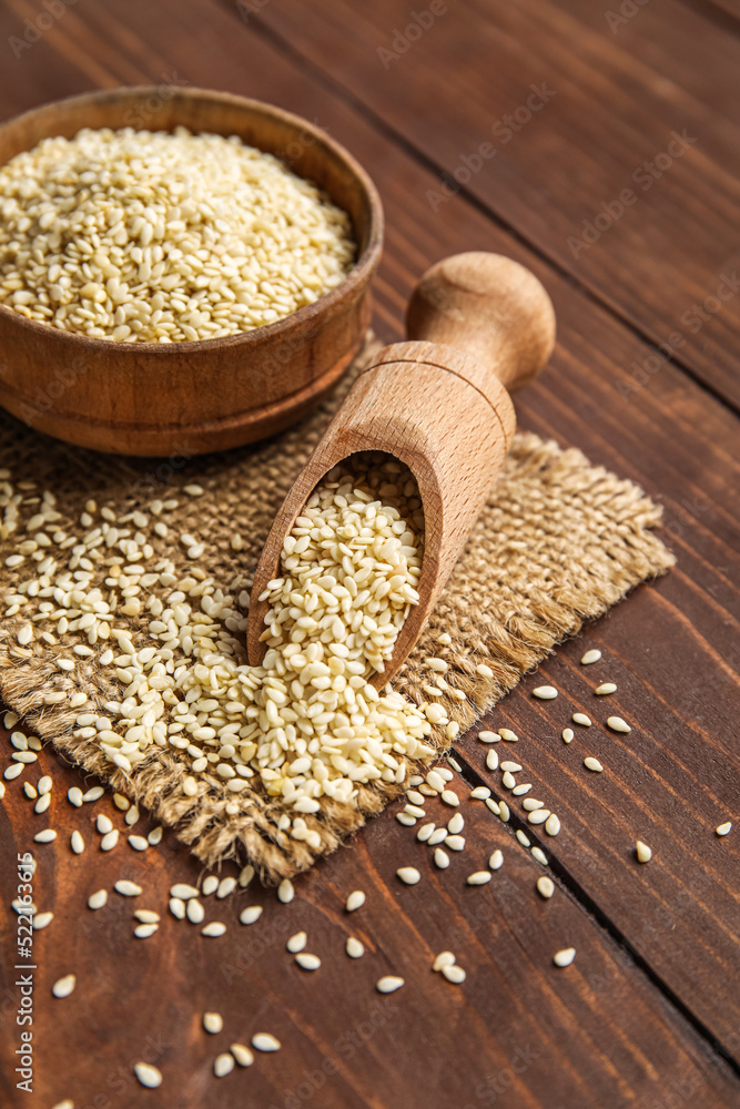 Bowl and scoop with sesame seeds on wooden background Bowl and scoop with sesame seeds on wooden background