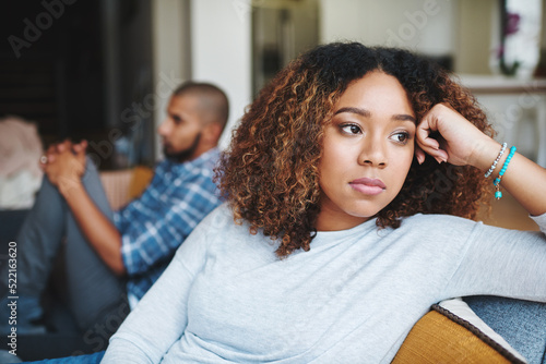 Unhappy couple and sad woman upset after argument or conflict with her man on home sofa. Angry girlfriend or female thinking about disagreement or ignoring partner, tired of relationship problems.