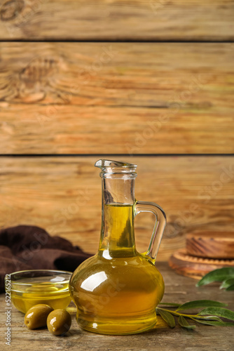 Decanter and bowl with fresh olive oil on wooden background