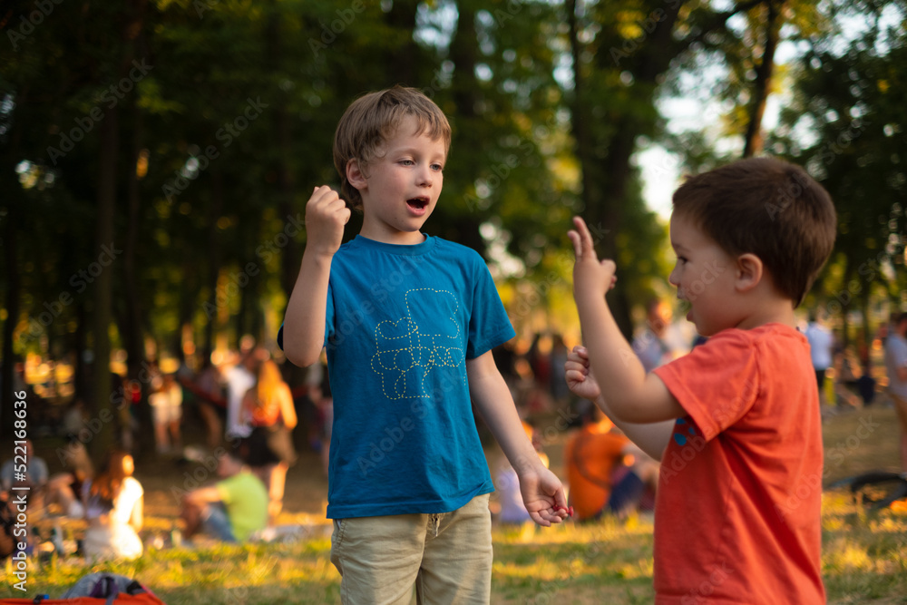 Kids are playing Rock, paper, scissors game in a park full of people
