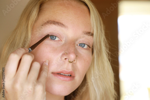 young woman applying eyeliner photo