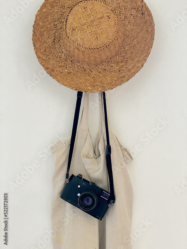 A straw hat, retro camera and a bag hang on a hanger  photo