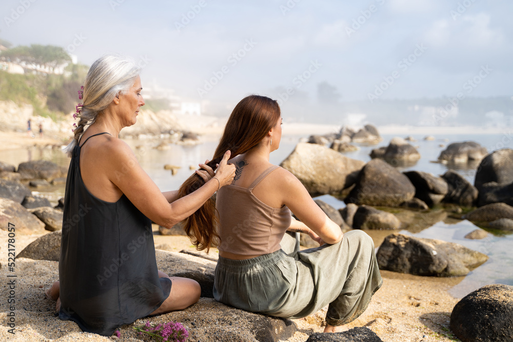 Mother braiding hair to daughter at the beach Mother braiding hair to daughter at the beach