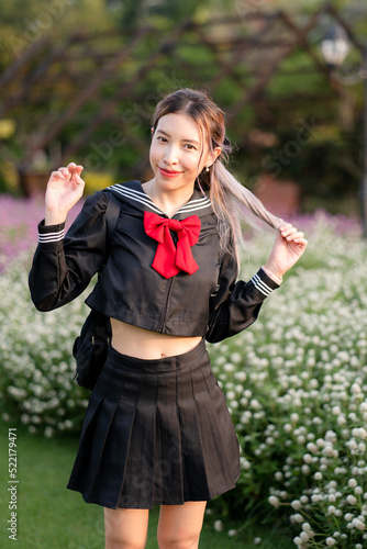 Woman wearing cosplay Japanese school uniform at park outdoor.