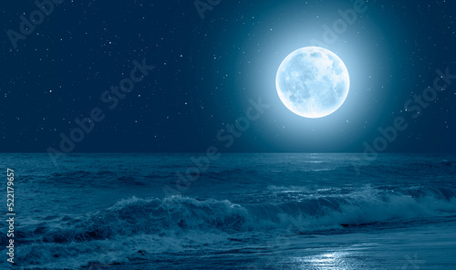 Night sky with blue moon in the clouds sea wave in the foreground 
