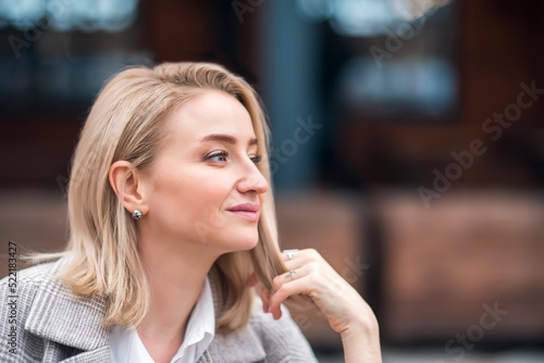 portrait of a beautiful blonde woman in a coat on the street. business woman