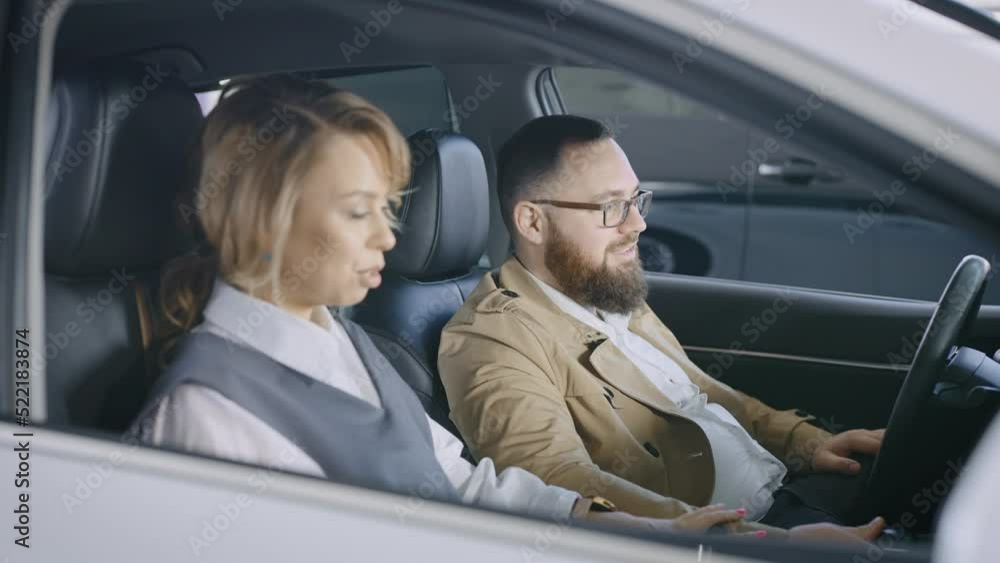 A married couple in the salon of a new car. Husband and wife are discussing buying a car from a car dealership. A married couple in the salon of a new car. Husband and wife are discussing buying a car from a car dealership.