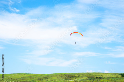 paragliding. extreme sport. a guy on a paraglider is flying in the blue sky. paraglider before landing