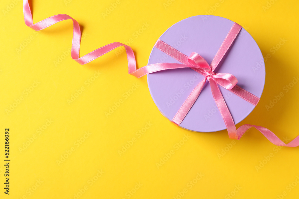 Round gift box with bow on yellow background Round gift box with bow on yellow background
