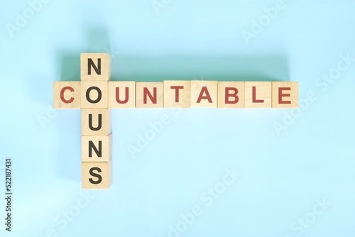 Countable nouns concept in English grammar noun education. Wooden block crossword puzzle flat lay in blue background. photo