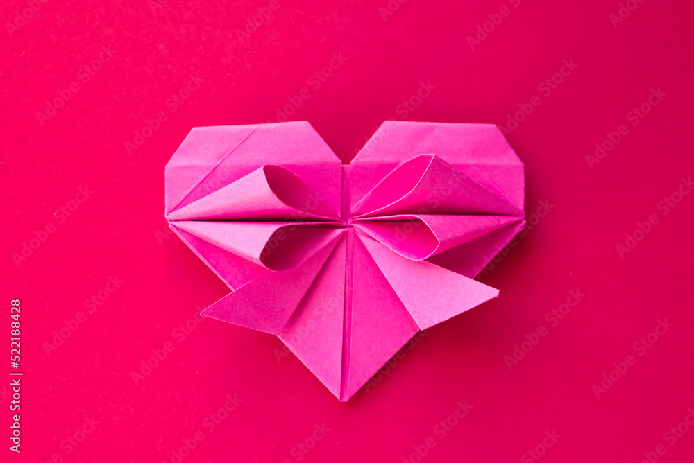 Pink paper heart origami isolated on a red background Pink paper heart origami isolated on a red background