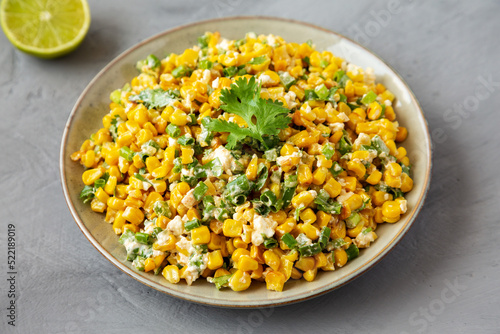 Homemade Mexican Street Corn Esquites on a Plate on a gray background, side view.