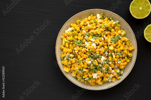 Homemade Mexican Street Corn Esquites on a Plate on a black background, top view. Flat lay, overhead, from above. Copy space.