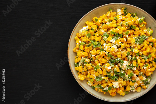 Homemade Mexican Street Corn Esquites on a Plate on a black background, top view. Flat lay, overhead, from above. Copy space.