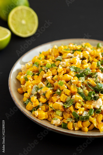 Homemade Mexican Street Corn Esquites on a Plate on a black background, side view. Close-up.