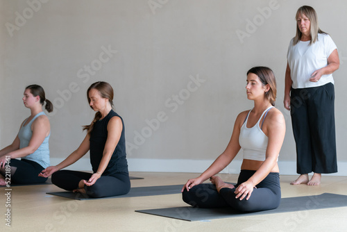 Yoga instructor leads class meditation in lotus position padmasana photo