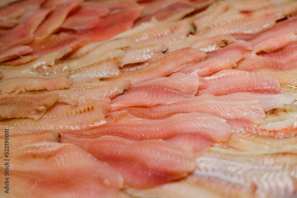 Lot of fish fillets lying on the counter in the shop window. Close-up, selective focus Lot of fish fillets lying on the counter in the shop window. Close-up, selective focus