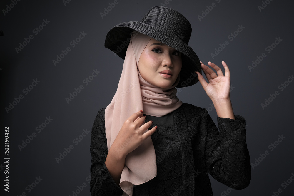 Portrait of a female wearing a hijab, a form of lifestyle garments for Muslim women, isolated on a dark background. Eid festive and hijab fashion concept Portrait of a female wearing a hijab, a form of lifestyle garments for Muslim women, isolated on a dark background. Eid festive and hijab fashion concept