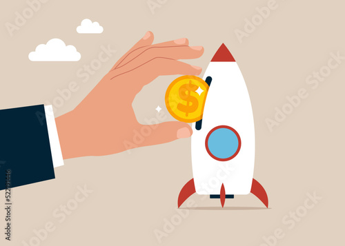 Businessman hand investor put money coin into innovative rocket to launch company. Funding startup company or venture capital investment.