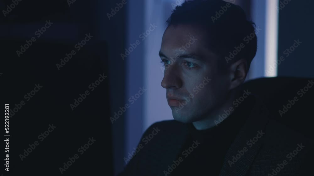 Young businessman man working at laptop computer late at night. Portrait of successful male entrepreneur searching the internet at night, the reflection of the monitor on his face Young businessman man working at laptop computer late at night. Portrait of successful male entrepreneur searching the internet at night, the reflection of the monitor on his face