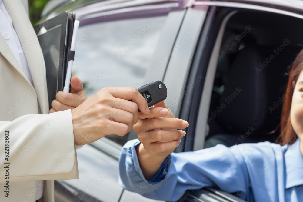 close up hand Beautiful young woman car salesman holding car keys and handing it to Asian female customer. close up hand Beautiful young woman car salesman holding car keys and handing it to Asian female customer.