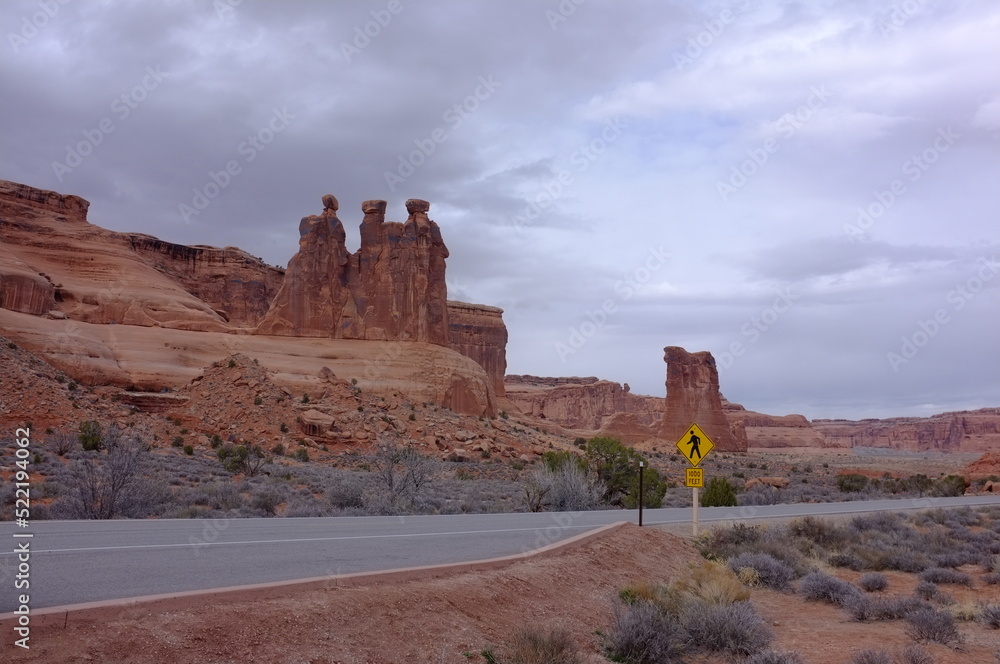 Photo of Three Gossips sandstone tower atop a pedestal within Courthouse Towers cluster in Arches National Park in Moab, Utah, United States USA done in works project administration style. Photo of Three Gossips sandstone tower atop a pedestal within Courthouse Towers cluster in Arches National Park in Moab, Utah, United States USA done in works project administration style.