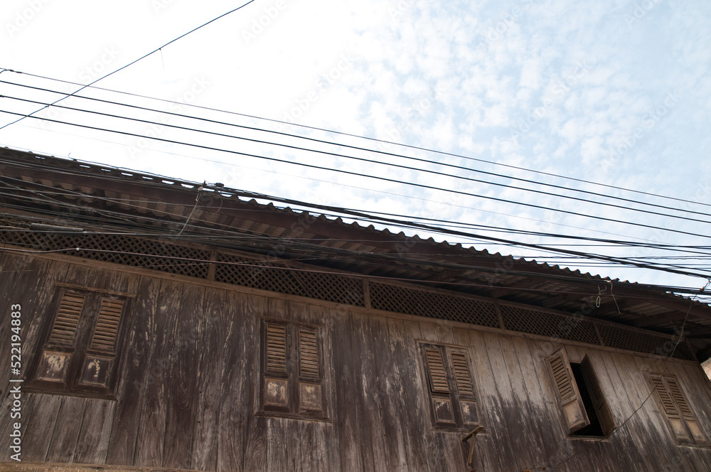 Thai style old traditional house with electrical wires on the top in cloudy day Thai style old traditional house with electrical wires on the top in cloudy day