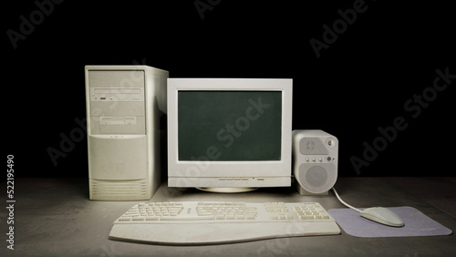 Old dirty computer with vintage monitor sitting on a dark table on a black background. With a vintage mouse, mousepad and keyboard. Next to a vintage old audio speaker. 3D rendering
