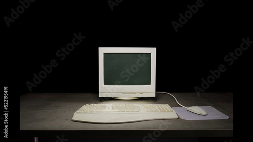Old dirty computer monitor sitting on a dark table on a black background. With a vintage mouse, mousepad and keyboard. 3D rendering