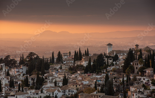 Evening cityscape view of the historic Moorish or Arab Quarter (Albaicín) in Granada with mountains in background, Andalusia, Spain. 