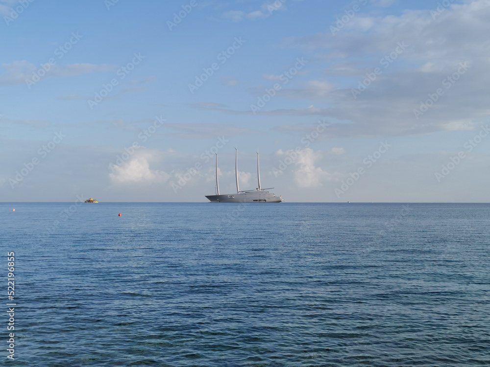The largest sailing yacht in the world, an eight-deck motorsailer on the Mediterranean coast against a blue sky with clouds.