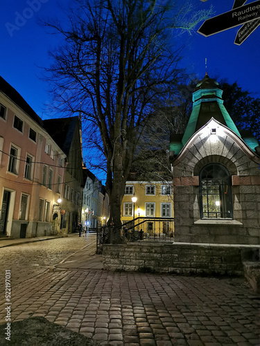 Old paved narrow street of Old Tallinn with a small chapel against the blue sky. Spring evening.