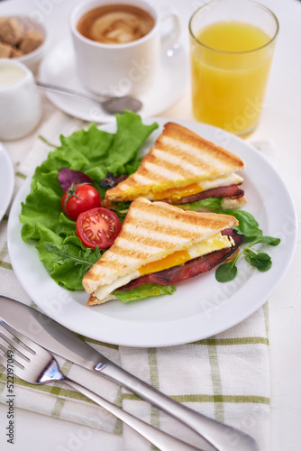 Tasty breakfast - sandwiches with fried eggs and bacon, coffe and glass of orange juice