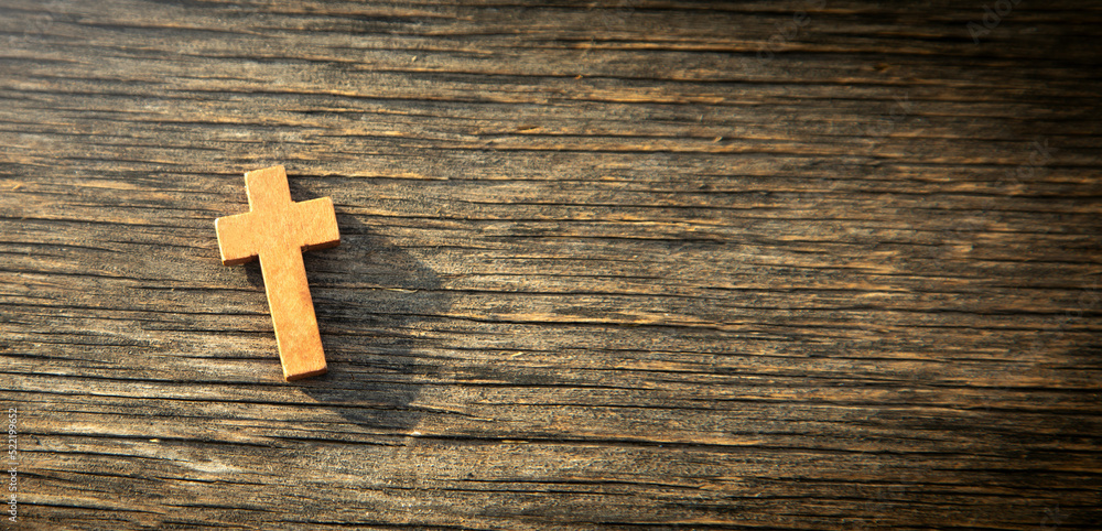 Christian cross on the wooden background.