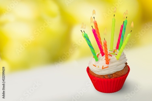 Tasty sweet buttercream birthday cupcake with colorful birthday candles and sprinkles