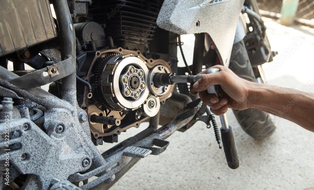 Mechanic repairing engine of motorcycle. Concept of motorcycle maintenance Mechanic repairing engine of motorcycle. Concept of motorcycle maintenance