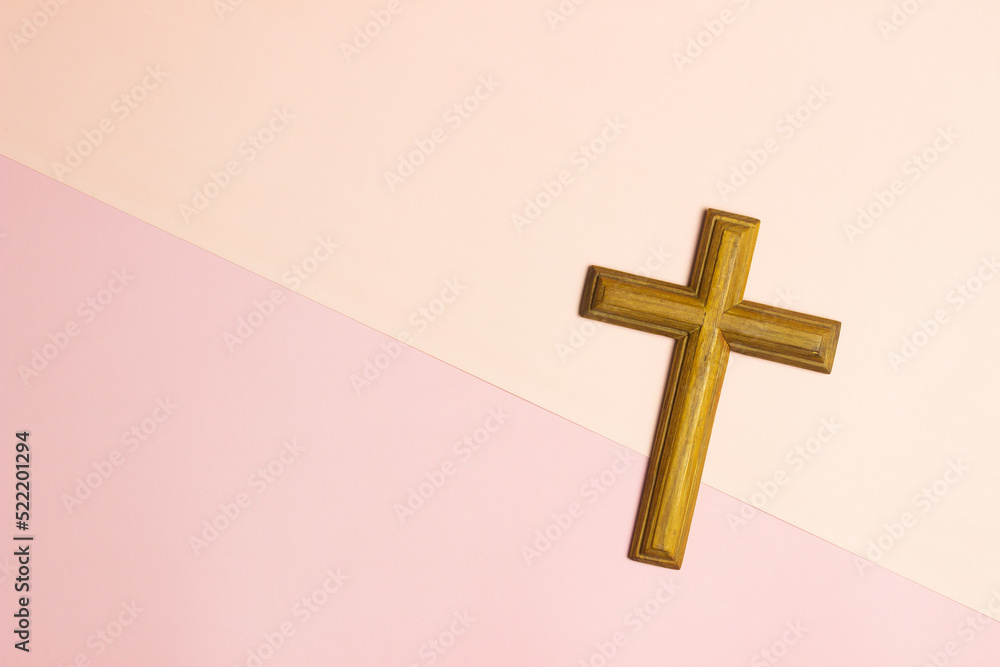 A wooden cross over the pink background with copy space.
