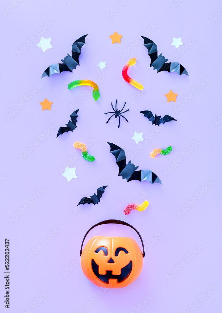 composition on the theme of the holiday Halloween bucket pumpkin sweets bats spiders on a light background