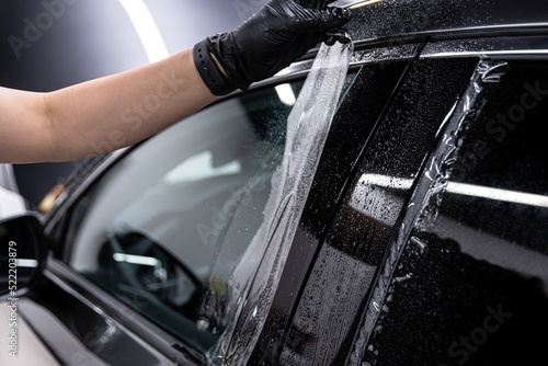 Obraz na płótnie employee of the car detailing studio protects the car body with a colorless protective film w salonie
