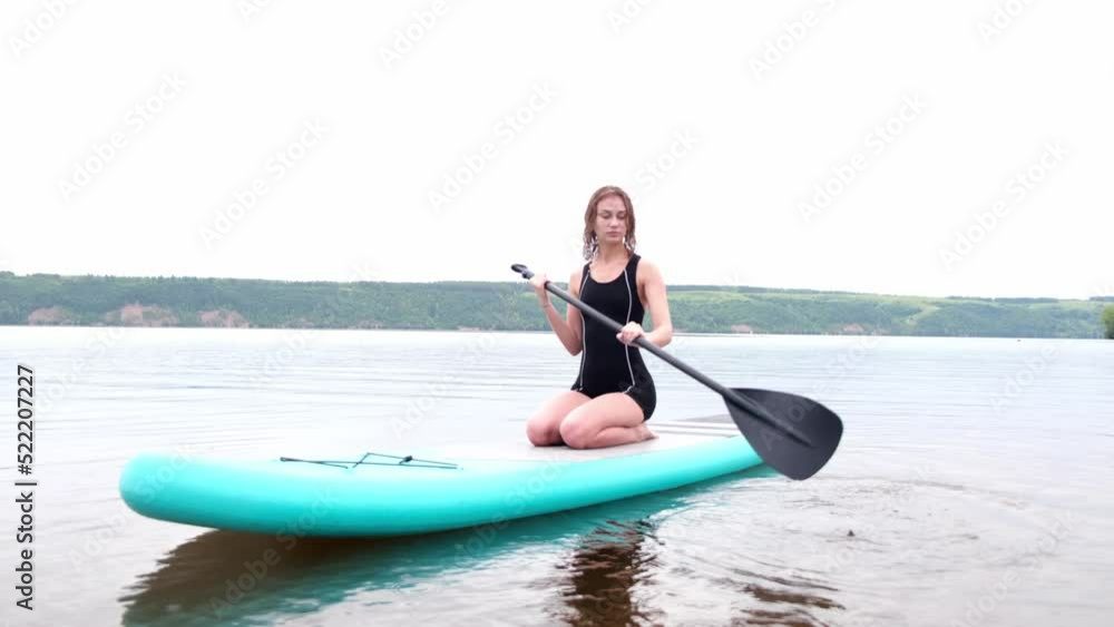A beautiful girl is floating on a supboard on a river. Young woman supsurfing at sunrise. A beautiful girl is floating on a supboard on a river. Young woman supsurfing at sunrise.