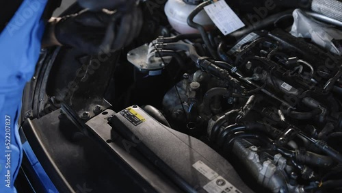 The car mechanic is checking the engine oil level. Overheating of car engine. Motor with open hood. Checking the engine oil car maintenance Remove the dipstick to view the engine oil level