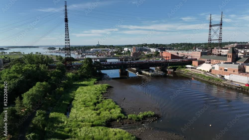 An aerial view by the Norwalk River Railroad Bridge on a sunny morning. The drone camera dolly in and pan right following a commuter train. An aerial view by the Norwalk River Railroad Bridge on a sunny morning. The drone camera dolly in and pan right following a commuter train.