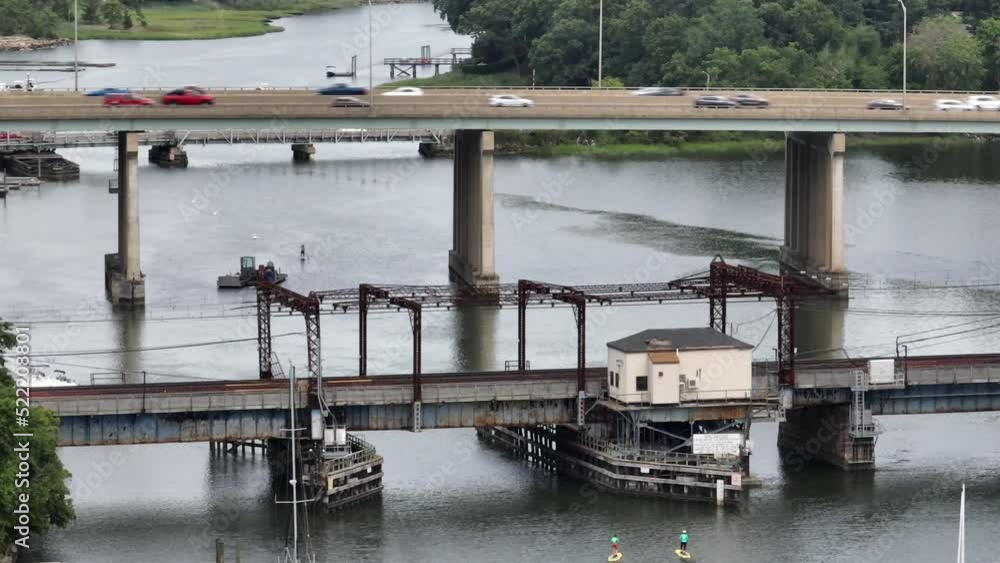 An aerial view of the Saugatuck River Railroad Bridge in CT on a cloudy day. The camera truck right and pan left, focused on the bridge as vehicles pass by on the elevated I-95 in the background. An aerial view of the Saugatuck River Railroad Bridge in CT on a cloudy day. The camera truck right and pan left, focused on the bridge as vehicles pass by on the elevated I-95 in the background.