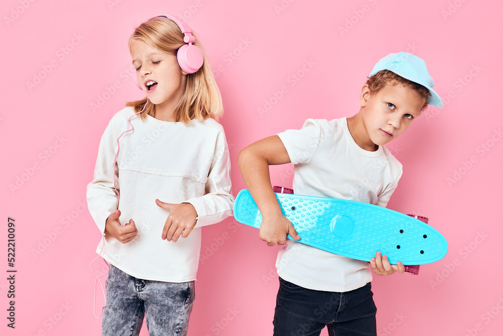 Stylish little boy and cute girl smiling and listening to music in headphones isolated background Stylish little boy and cute girl smiling and listening to music in headphones isolated background