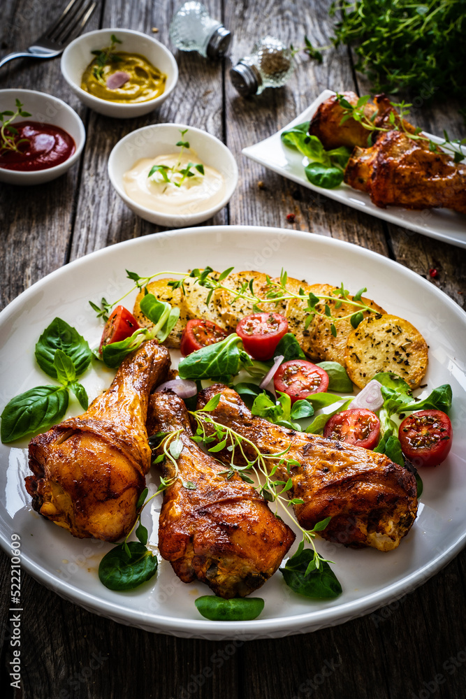 Barbecue chicken drumsticks with fried potato, lettuce and mini tomatoes on wooden table
Barbecue chicken drumsticks with fried potato, lettuce and mini tomatoes on wooden table